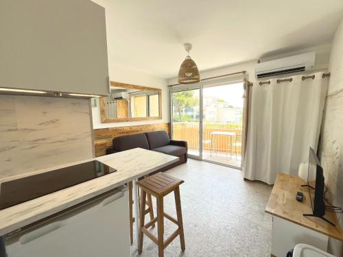une cuisine avec un comptoir et un tabouret dans une pièce dans l'établissement Studio refait en 2024 avec terrasse, climatisation et parking, à 50m de la plage - FR-1-338-588, à Sète