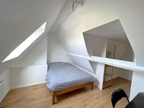Cette chambre mansardée comprend un lit et un bureau. dans l'établissement **Duplex Lumineux à Deux Pas de la Plage et Commerces - Berck** - FR-1-646-76, à Berck-sur-Mer