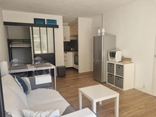 un salon avec un canapé blanc et une cuisine dans l'établissement Appartement rénové à Seignosse : Plage et commerces à pied, terrasse et wifi inclus - FR-1-239-1081, à Seignosse