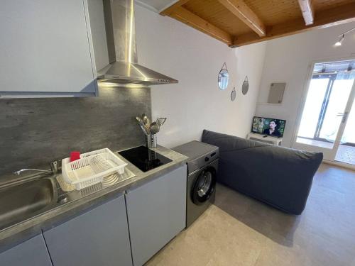 une cuisine avec un évier et un canapé dans une chambre dans l'établissement Pavillon climatisé avec mezzanine, 4 couchages, proche plage et commerces, parking privé, St-Cyprien - FR-1-106-105, à Saint-Cyprien