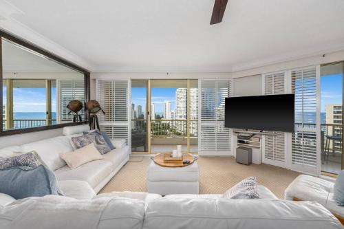 a living room with a white couch and a flat screen tv at Contessa Queen in Gold Coast