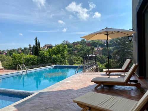 a swimming pool with a chair and an umbrella at Lovely 3BD 4BA APT Pool Gym Parking in San Miguel de Allende