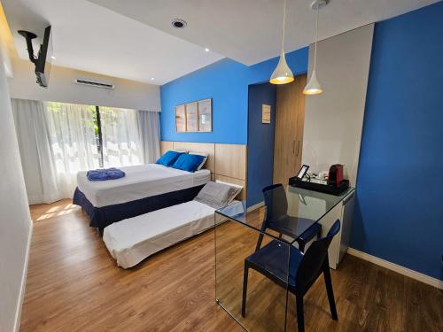 a blue room with two beds and a glass table at Mercure Recife Navegantes - Privado in Recife
