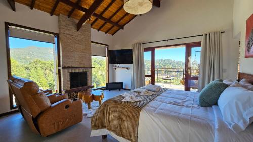 a bedroom with a large bed and a fireplace at Chalés Mirante Monte Verde in Monte Verde