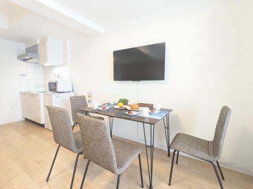 a dining room table with chairs and a television on the wall at ESLEAD HOTEL Namba South Ⅰ in Osaka