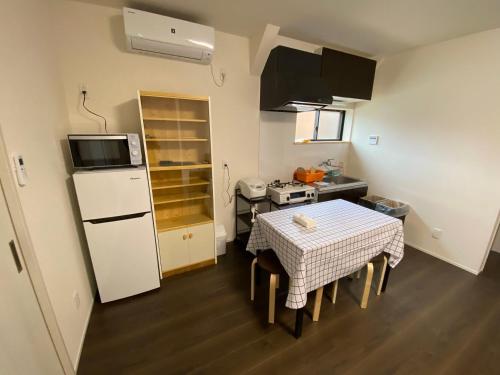 a small kitchen with a table and a white refrigerator at 高島市一棟貸切 Biwa Lake琵琶湖 徒歩0分 大人数でご利用だとお得連泊がお得BBQ自転車無料利用可ペット可 in Takashima