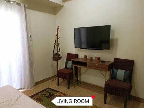 a living room with a desk and a flat screen tv at Newly Opened Cozy Studio Near Airport in Iloilo City