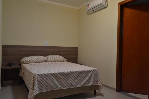 a bedroom with a bed with a wooden headboard at Hotel Vilamoura in Sao Paulo