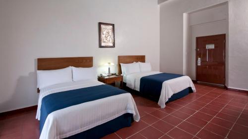 a hotel room with two beds with white and blue sheets at Holiday Inn Veracruz-Centro Historico by IHG in Veracruz