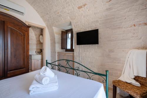 a bedroom with a bed and a tv on a brick wall at Trulli Contento - Rooms & Apartments in Alberobello