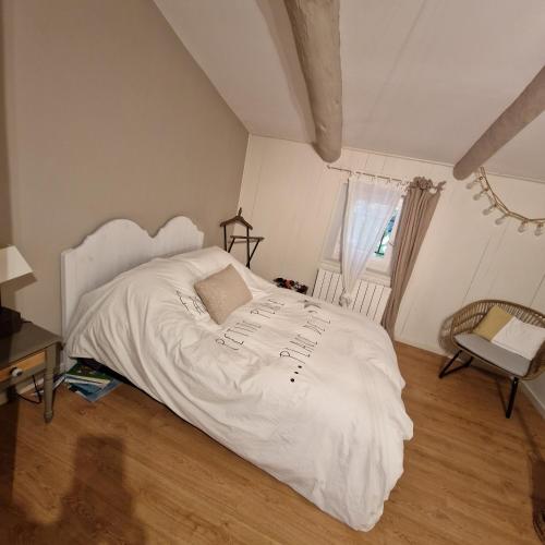 a bedroom with a white bed and a chair at chambre entre Nesque et Ventoux in Mormoiron