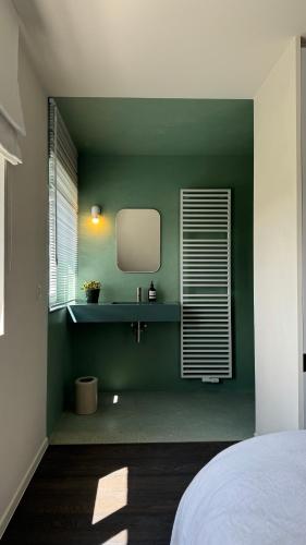 a bedroom with a green wall with a mirror at House W - North Sea Stays in De Haan