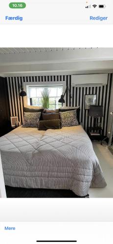 een slaapkamer met een groot bed met gestreepte muren bij Charming Cottage Within Walking To Beach in Holeby