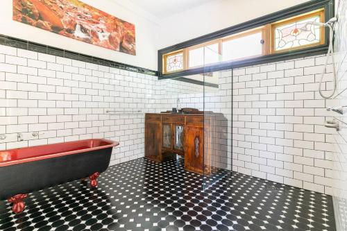 un bagno con una vasca rossa e piastrelle bianche e nere di Riverwood Cottage, accessible accommodation a Warburton