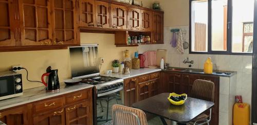 阿斯马拉Guest House in Asmera的厨房配有木制橱柜和小桌子。