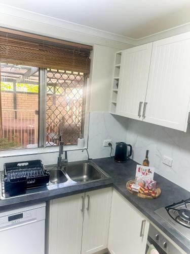 a small kitchen with a sink and a window at Queen of the Desert Villa Secure & Gated 2 Bedrooms in Alice Springs