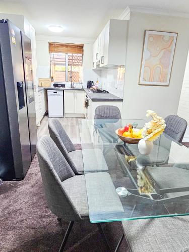 a living room with a glass table and a kitchen at Queen of the Desert Villa Secure & Gated 2 Bedrooms in Alice Springs