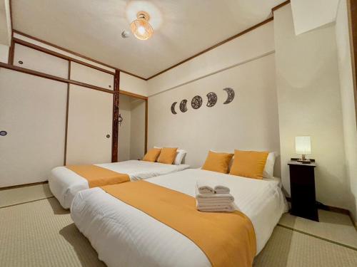 a bedroom with two beds with orange and white sheets at Neighbor's Hotel 広島駅北口 in Hiroshima
