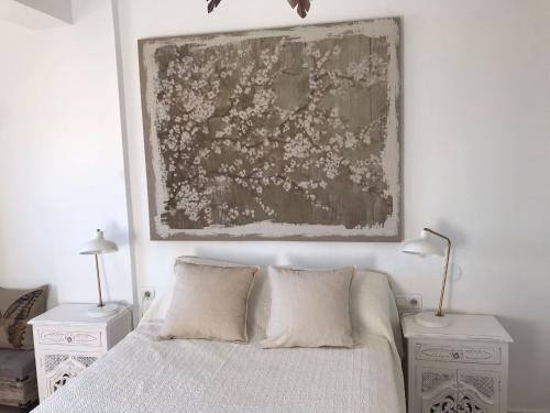 a bedroom with a bed with two night stands and a painting on the wall at Mirando al Mar con Wifi y Terraza 1ª línea playa in Cádiz