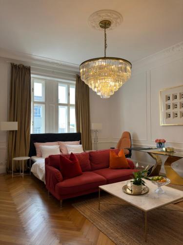 a living room with a red couch and a chandelier at Royal Residence Schönbrunn in Vienna