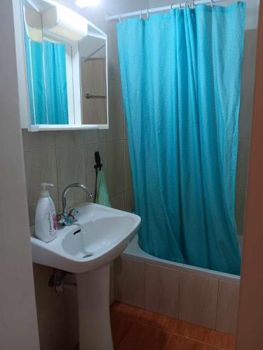 a bathroom with a sink and a blue shower curtain at Summer Bliss Apartment Peyia in Peyia