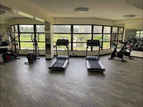 a gym with several treadmills and elliptical machines at Zoe Homes Westpointe Suites 1 and 2 bedroom Nairobi West Estate Mbagathi Way Madaraka Estate Strathmore University in Nairobi