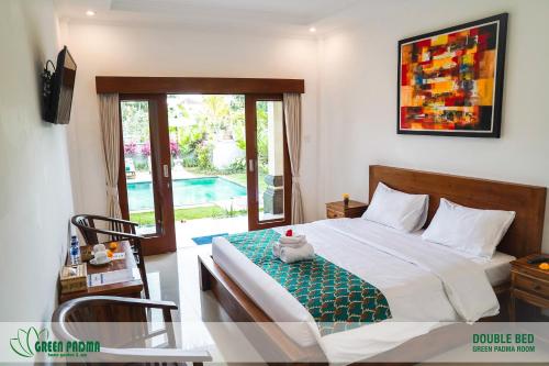 a bedroom with a bed and a table and a window at Green Padma Ubud in Ubud