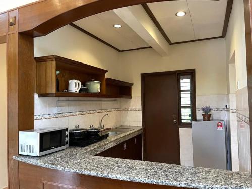 a kitchen with a counter with a microwave and a refrigerator at A'Famosa Villas in Ayer Keroh