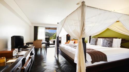 a bedroom with a canopy bed and a living room at Relax Resort Hotel in Atami