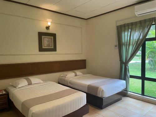 two beds in a room with a window at A'Famosa Villas in Ayer Keroh