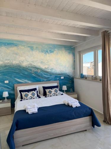 a bedroom with a large bed with a painting on the wall at Terrasini Sea in Terrasini