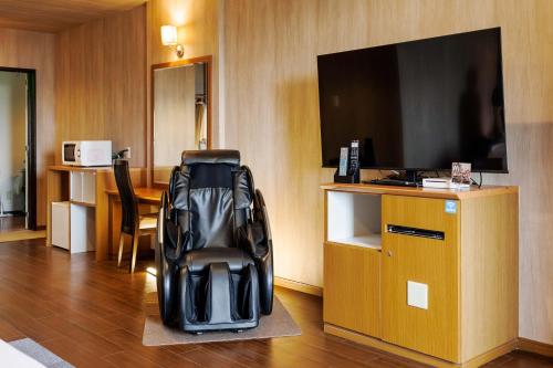 a hotel room with a chair and a flat screen tv at Hotel 4Season in Miyazaki