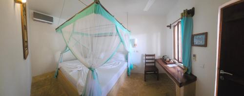 a bedroom with a canopy bed and a table at Kiganja in Matemwe