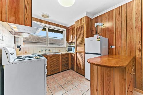 Una cocina con refrigerador blanco y gabinetes de madera. en Retro Retreat - Mornington, en Mornington