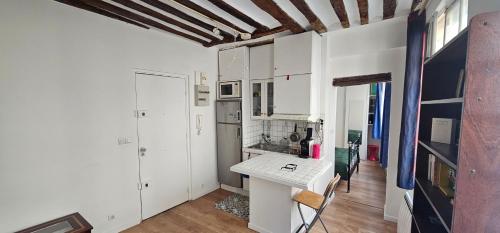 une cuisine avec des armoires blanches et une table blanche dans l'établissement Appartement Fontaines - Soutar Prestige, à Paris