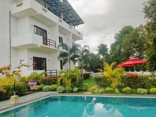 una villa con piscina frente a una casa en Hotel Veena, en Pillagoda