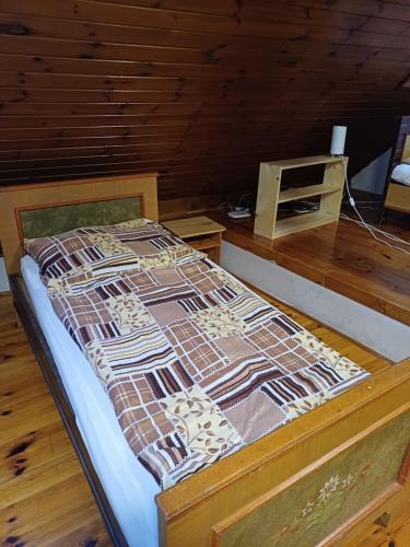 a bed in a room with a wooden floor at Zanati Apartmannház in Nagykapornak