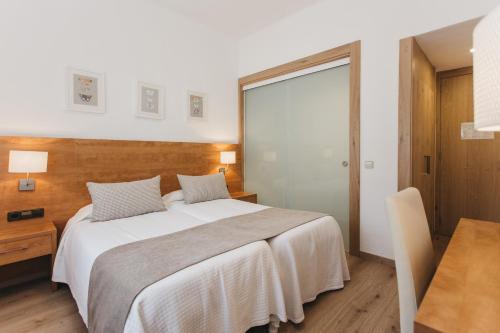 a bedroom with a large bed and a desk and a window at Hotel Catalunya Park in Ribes de Freser