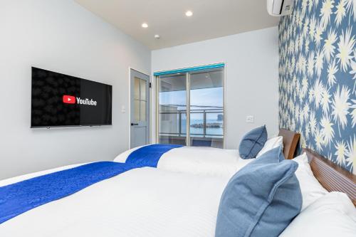 a bedroom with two beds and a flat screen tv at Daikyo Engtsuto Villa in Shirahama