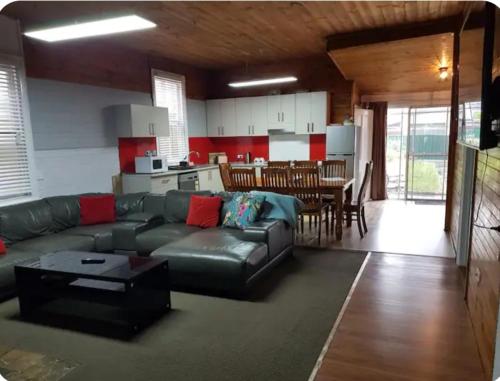 a living room with a leather couch and a kitchen at 4 Bedroom Federation Cottage in Lithgow