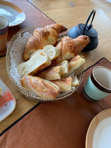 une assiette de pain et de croissants sur une table dans l'établissement Les Herbes Flottantes, à Englesqueville-en-Auge