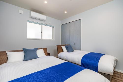 a bedroom with two beds and a window at Daikyo Engtsuto Villa in Shirahama