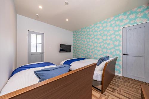 two beds in a bedroom with blue and green wallpaper at Daikyo Engtsuto Villa in Shirahama