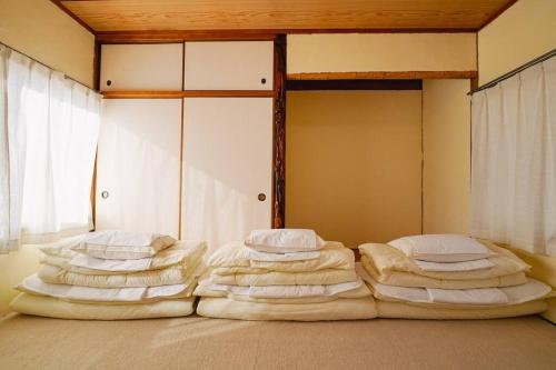 zwei Stapel Kissen auf einem Bett in einem Zimmer in der Unterkunft 香川県高松市中心部で駐車6台無料の家族向けゲストハウス in Takamatsu