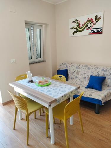 a dining room with a table and chairs and a couch at Casa Acquamarina in Marina di Monasterace