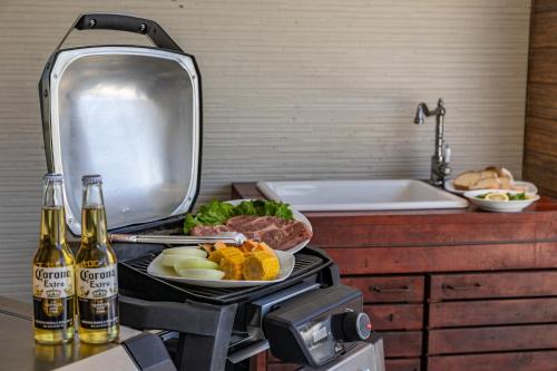 a grill with a plate of food and bottles of beer at Daikyo Engtsuto Villa in Shirahama