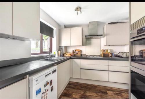 a large white kitchen with white cabinets and appliances at Oxford University Centre Lovely House in Oxford
