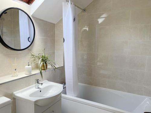 a bathroom with a sink and a tub and a mirror at Oxford University Centre Lovely House in Oxford