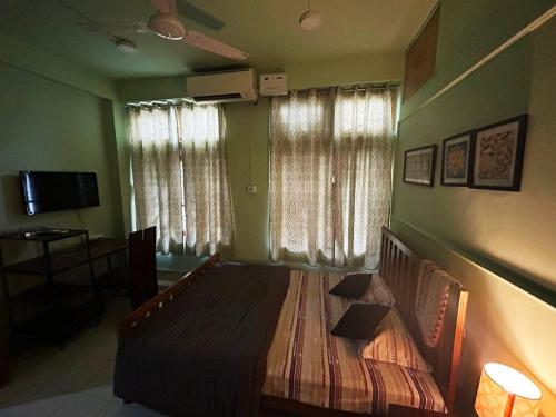 a bedroom with a bed in a room with windows at BimBan's- A cozy little place in Guwahati
