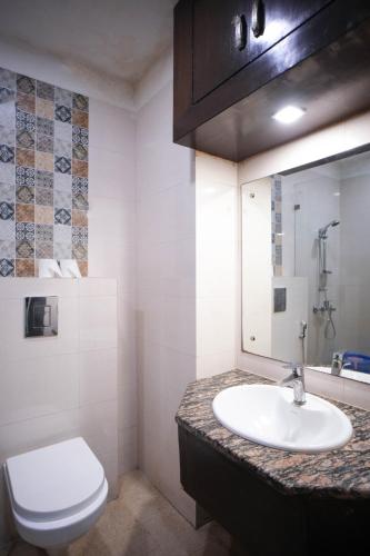 a bathroom with a white toilet and a sink at Hotel Haris MG Road Gurugram in Gurgaon